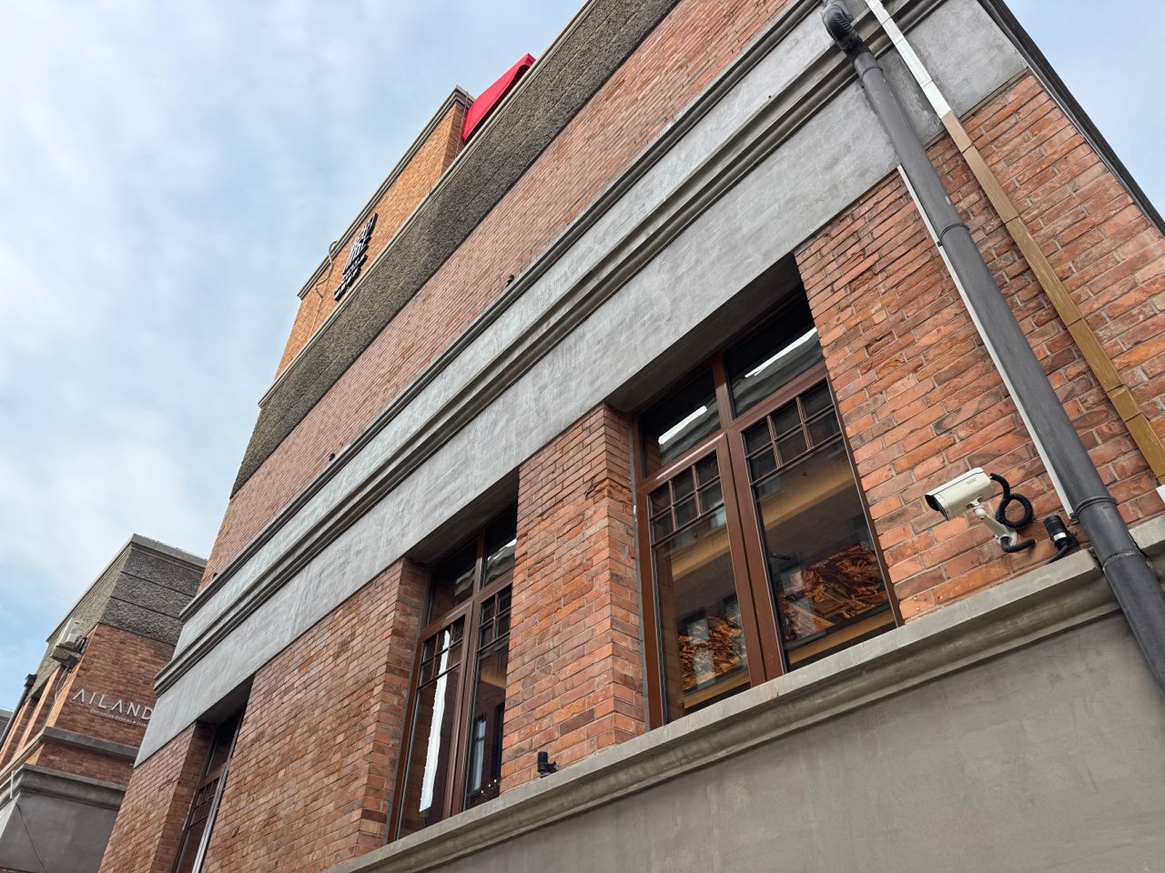 Services Low angle view of a red brick building facade with windows and a security camera.